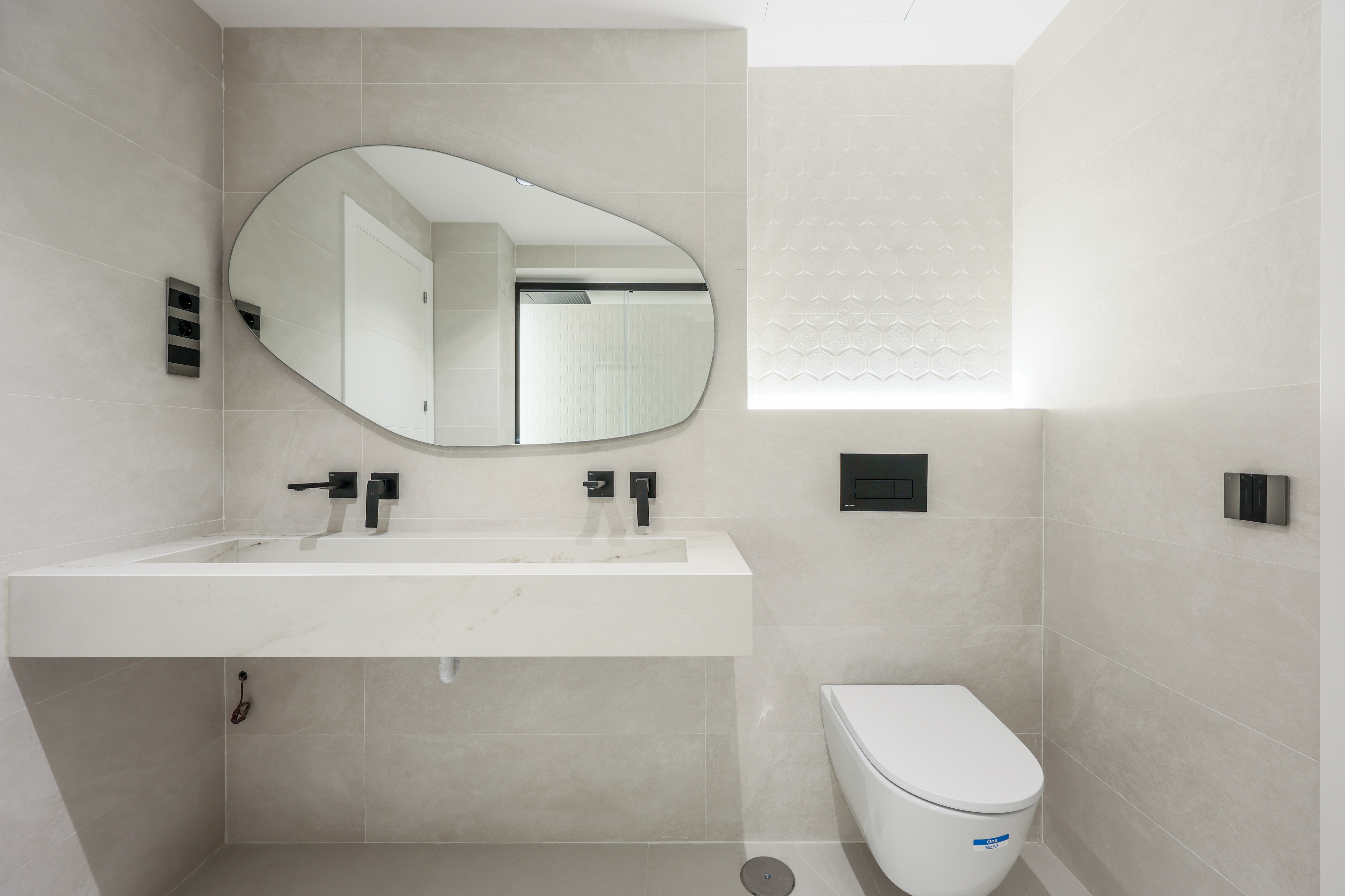 Aseo de mármol blanco con lavabo ovalado y espejo circular retroiluminado