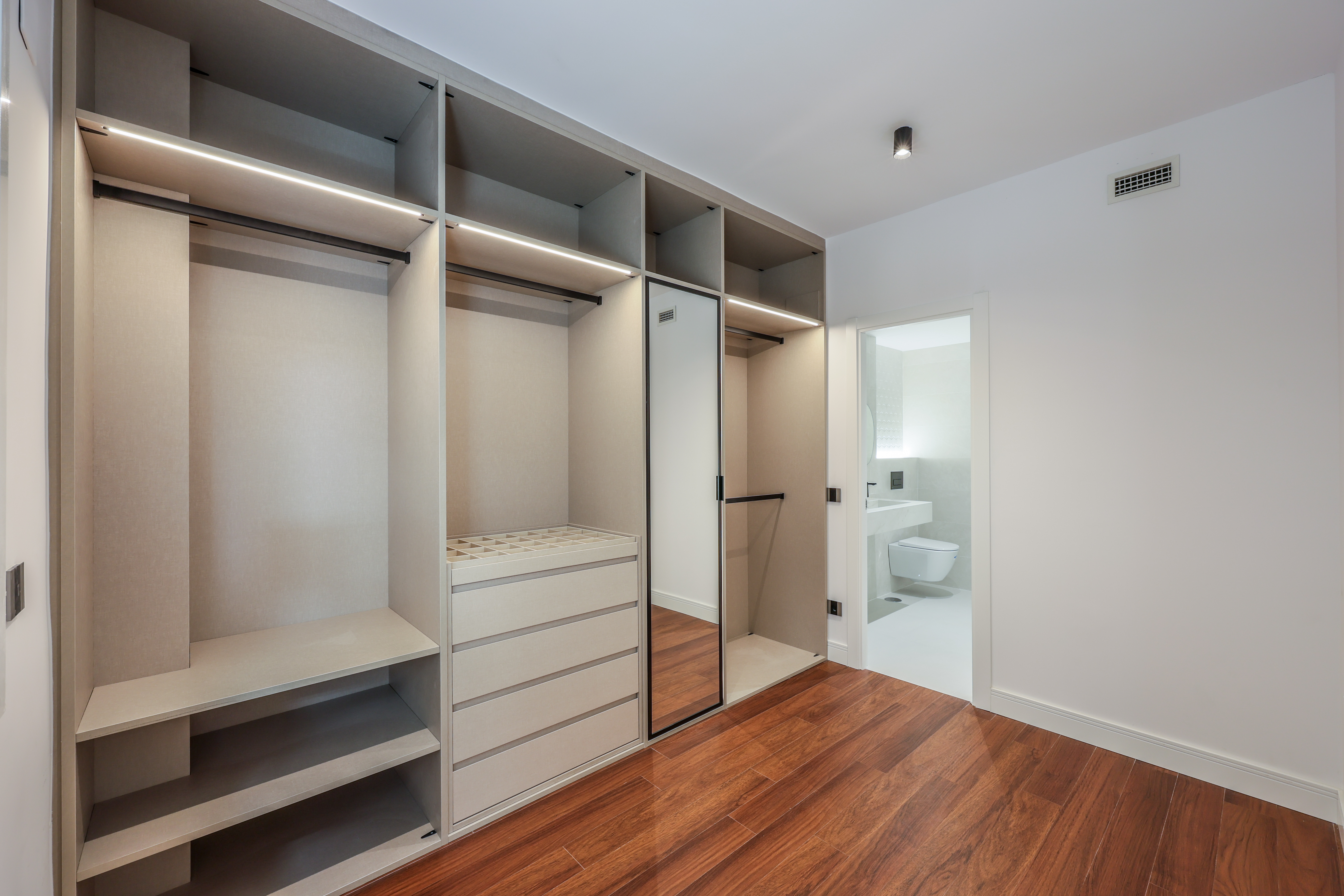 Vestidor con estanterías y armario abierto, suelo de madera