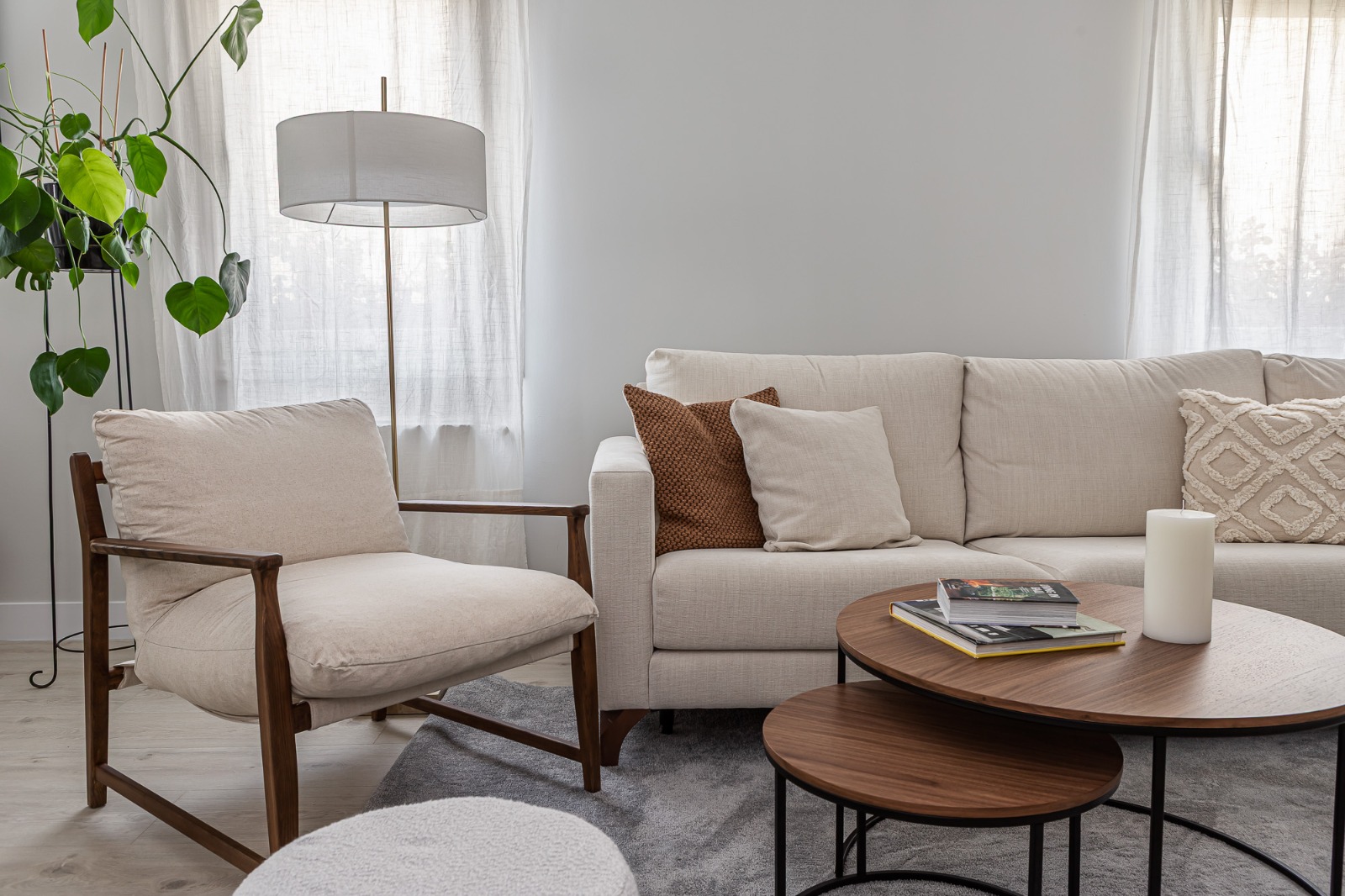 Salón con sofá beige, sillón de madera y mesas de centro redondas