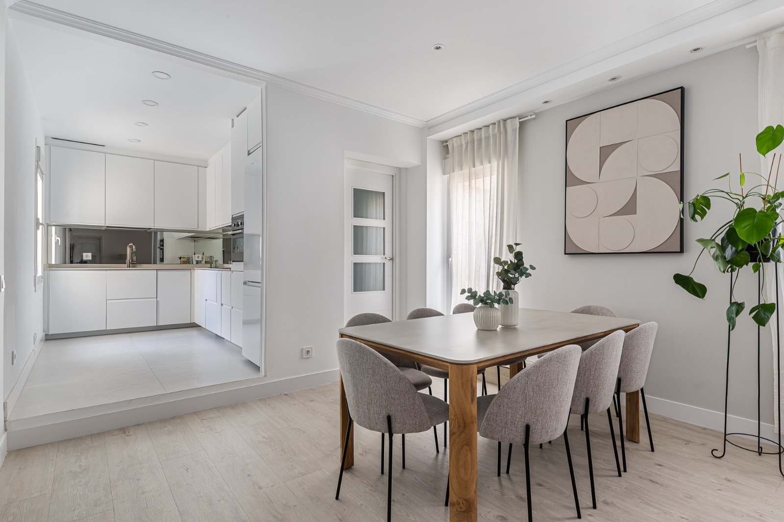 Cocina abierta y zona de comedor con mesa de madera y sillas tapizadas en gris — Vivienda Fernán González