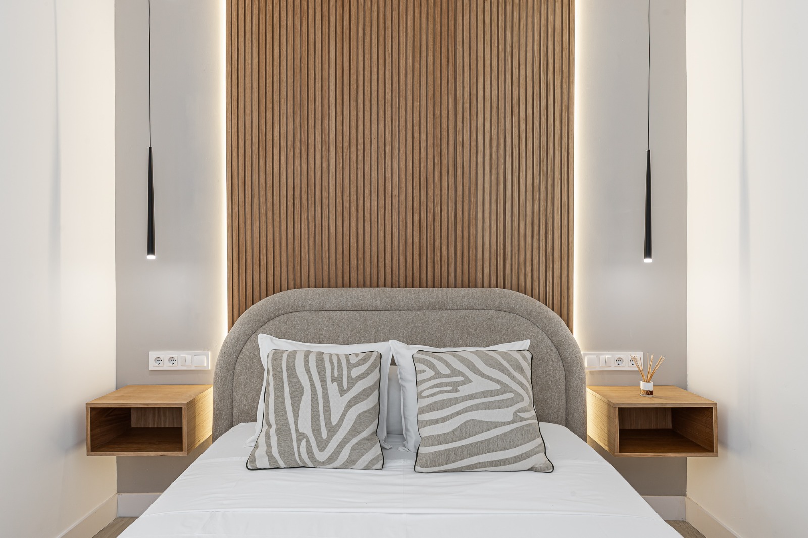 Dormitorio principal con cabecero de listones de madera y lámparas colgantes